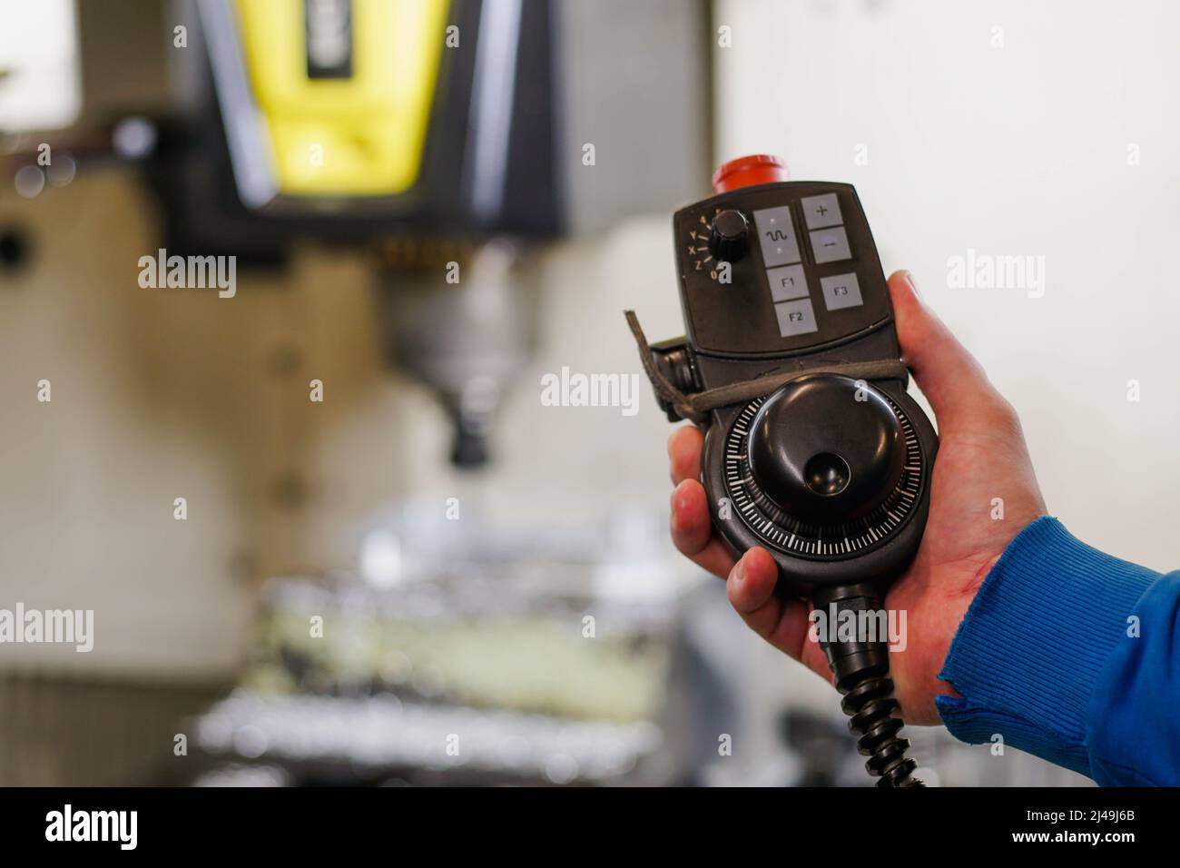 L'operatore tiene il pannello di controllo della rotazione per il parametro di regolazione della precisione della macchina del centro di lavoro cnc. Foto Stock