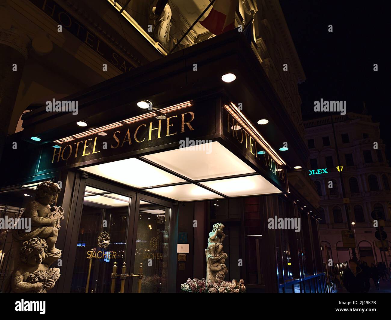 Vista dell'ingresso dell'edificio del famoso alloggio di lusso Hotel Sacher nel centro storico di Vienna, Austria di notte con scritte dorate. Foto Stock