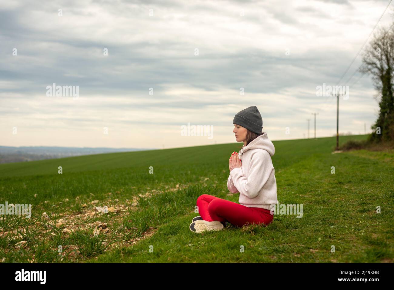 Donna seduta in lotus posa fare yoga all'aperto Foto Stock