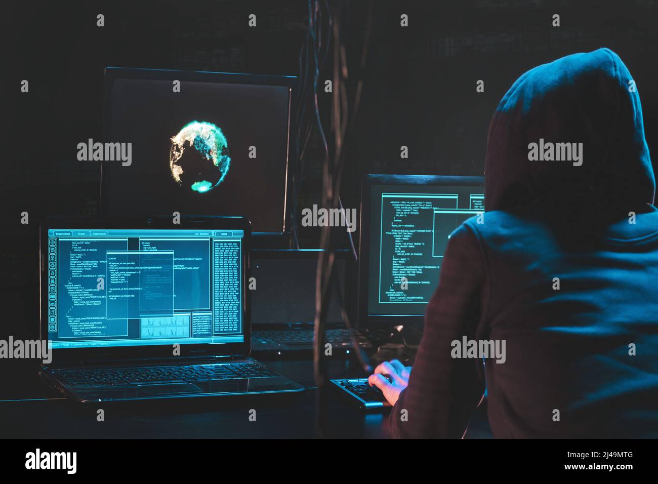 Hacker con attacco posteriore che utilizza software dannoso hack data center aziendale. Malefactor nascosto sottoterra in un luogo buio, più display con phishing Foto Stock