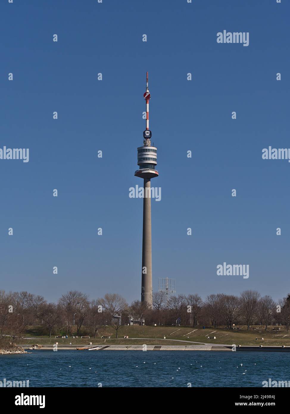 Splendida vista della famosa torre Donauturm a Vienna, Austria, sulla riva del fiume Danubio in giornata di sole nella stagione primaverile vista dall'isola del Danubio. Foto Stock