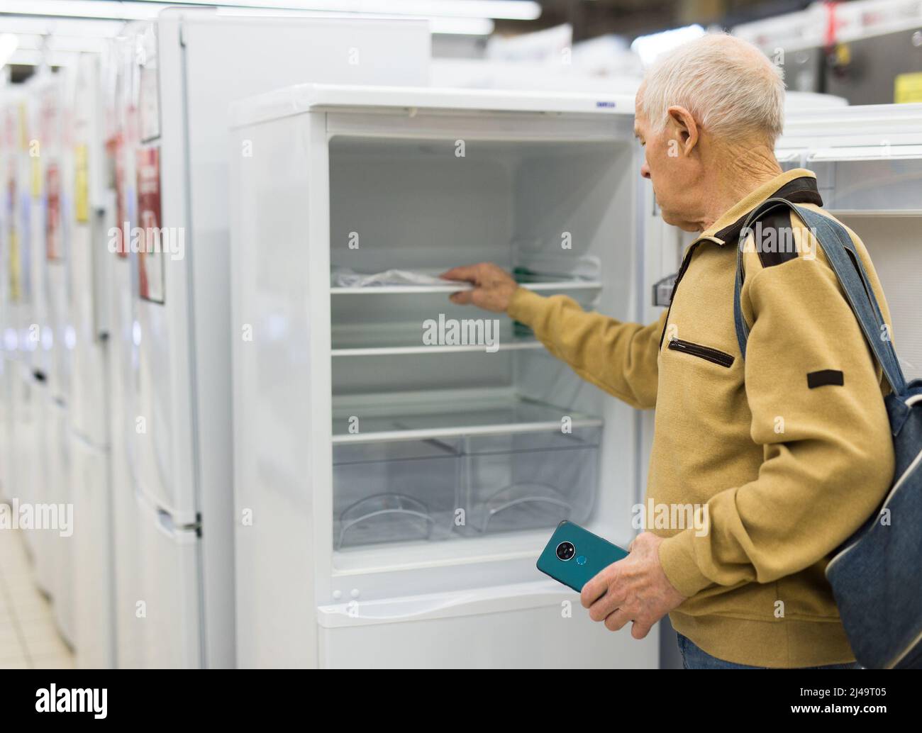 senor uomo pensionato acquistare frigorifero in showroom di elettrodomestici negozio Foto Stock