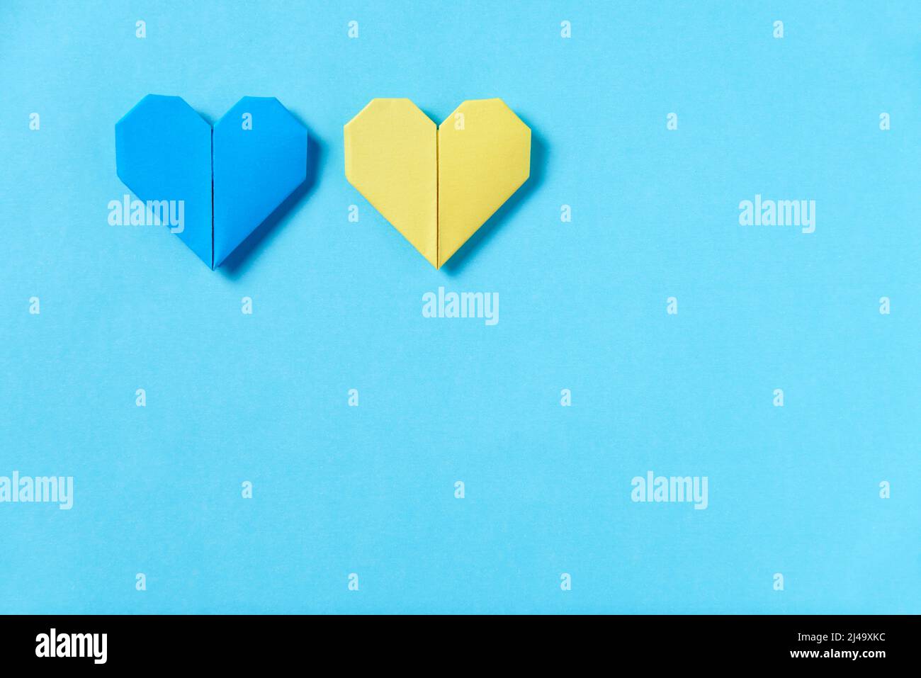Cuori di origami blu e giallo, colori della bandiera Ucraina. Immagine simbolica concettuale a sostegno di questo paese durante l'invasione russa. Desidera f Foto Stock