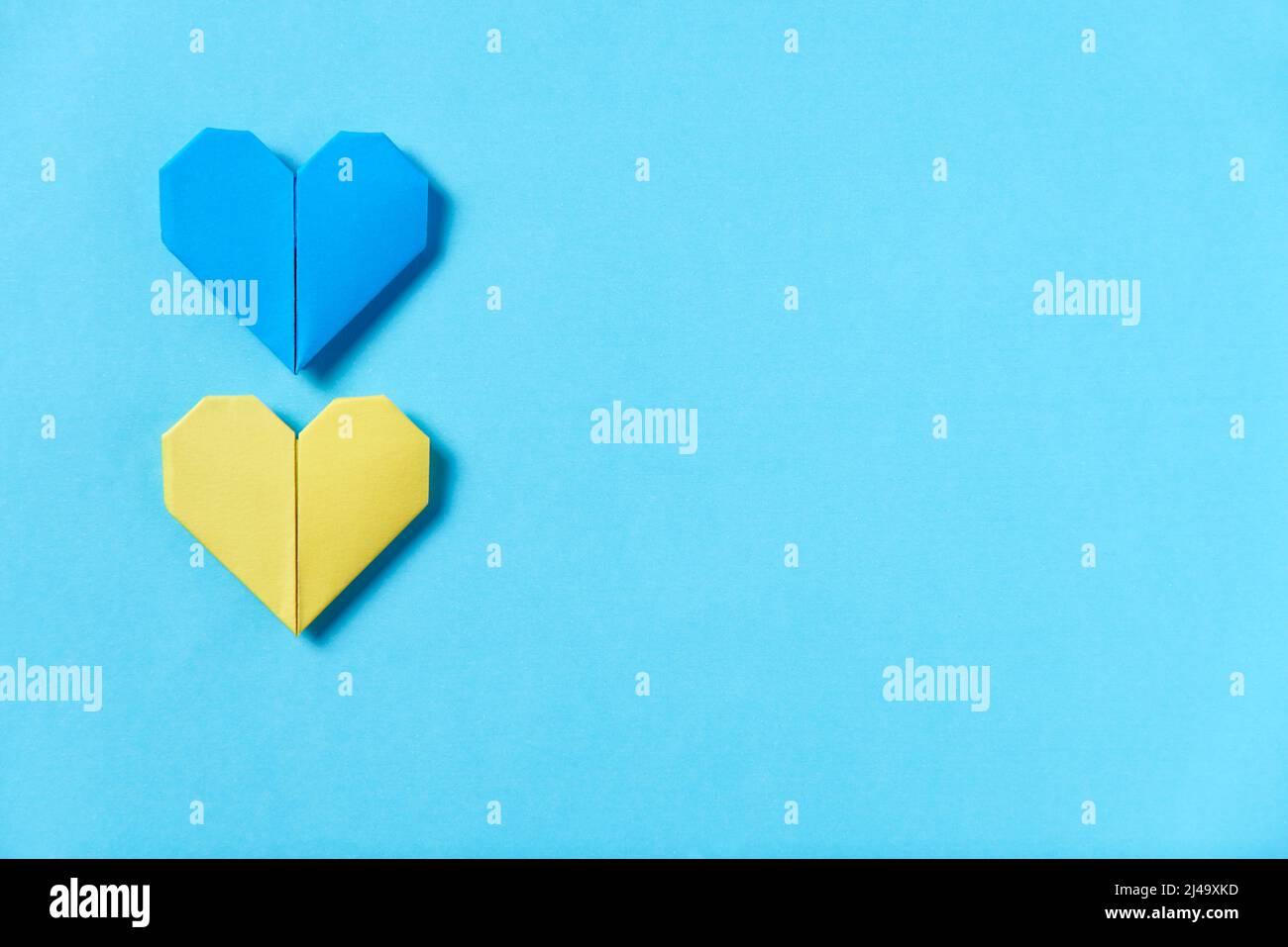 Cuori di origami blu e giallo, colori della bandiera Ucraina. Immagine simbolica concettuale a sostegno di questo paese durante l'occupazione russa. Desiderio Foto Stock