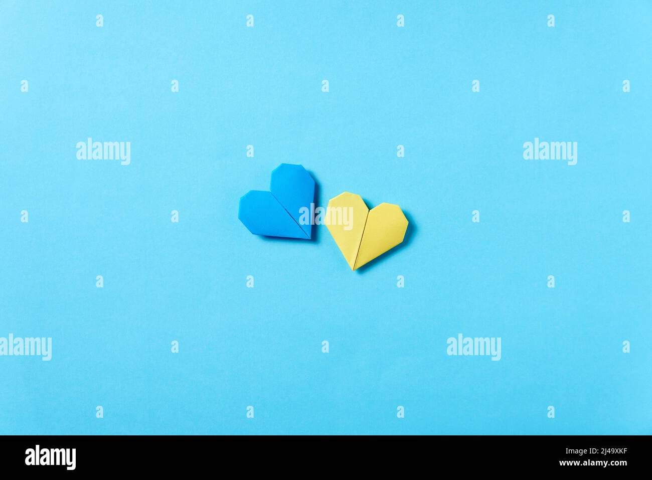 Cuori di origami blu e giallo, colori della bandiera Ucraina. Immagine simbolica concettuale a sostegno di questo paese durante l'invasione militare russa Foto Stock