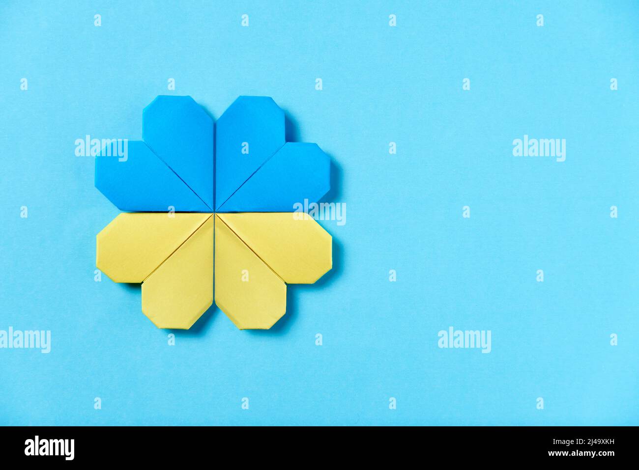 Fiore di origami blu e giallo, colori della bandiera Ucraina. Immagine simbolica concettuale a sostegno dell'Ucraina durante l'aggressione militare russa. Foto Stock