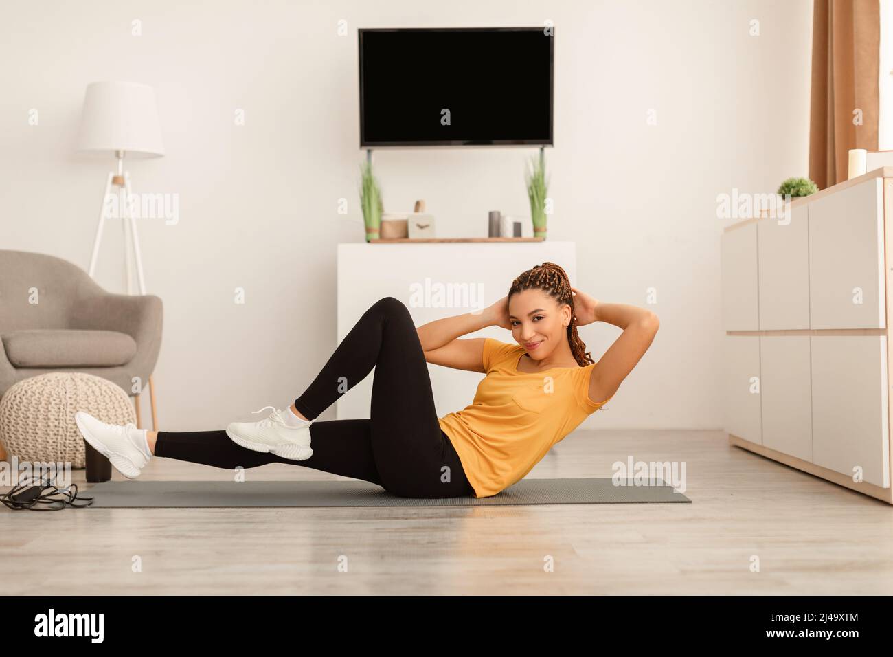 Donna Africana che fa il gomito a ginocchio ABS crunches Indoor Foto Stock