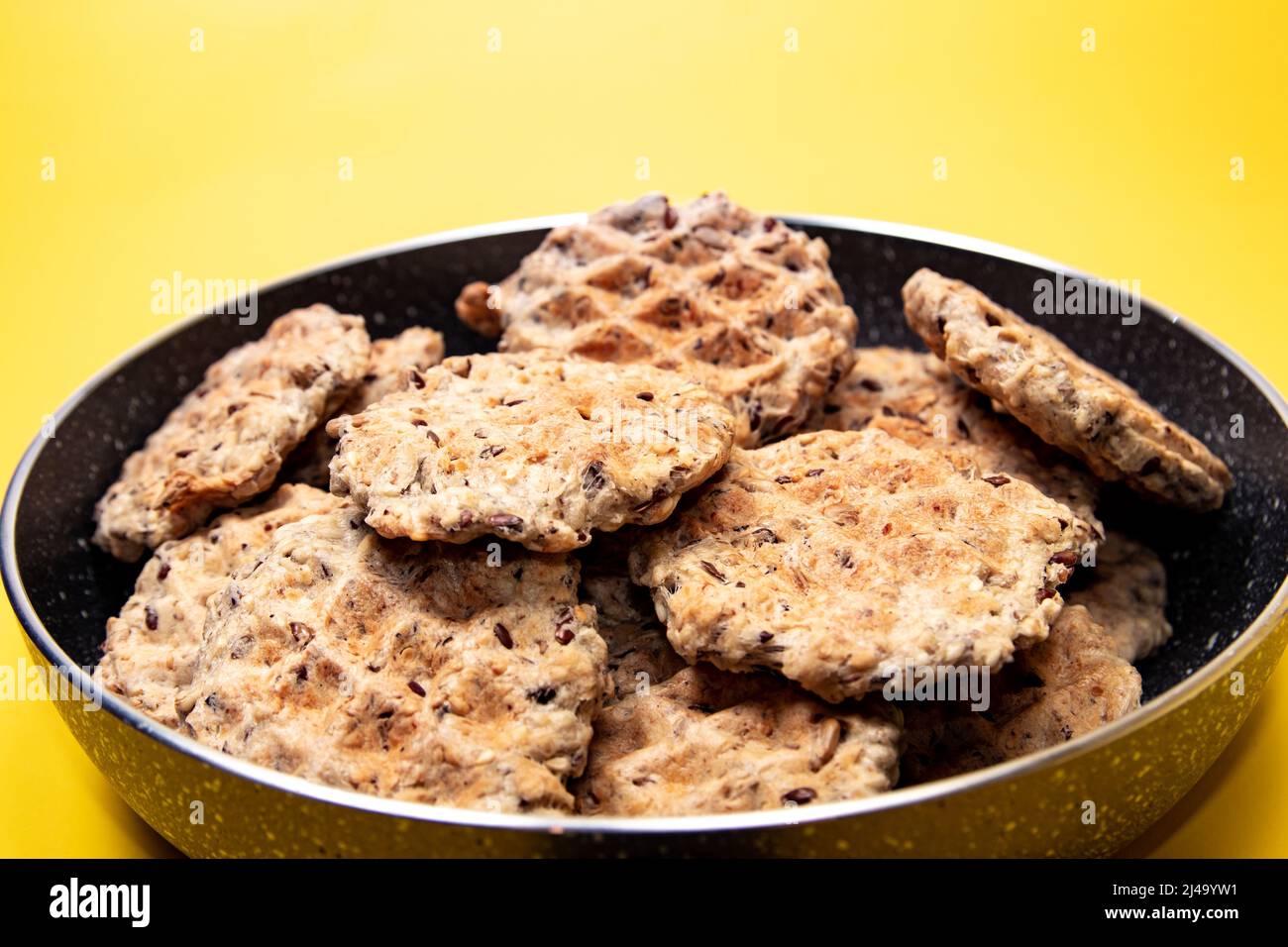 Waffle in una padella su sfondo giallo Foto Stock