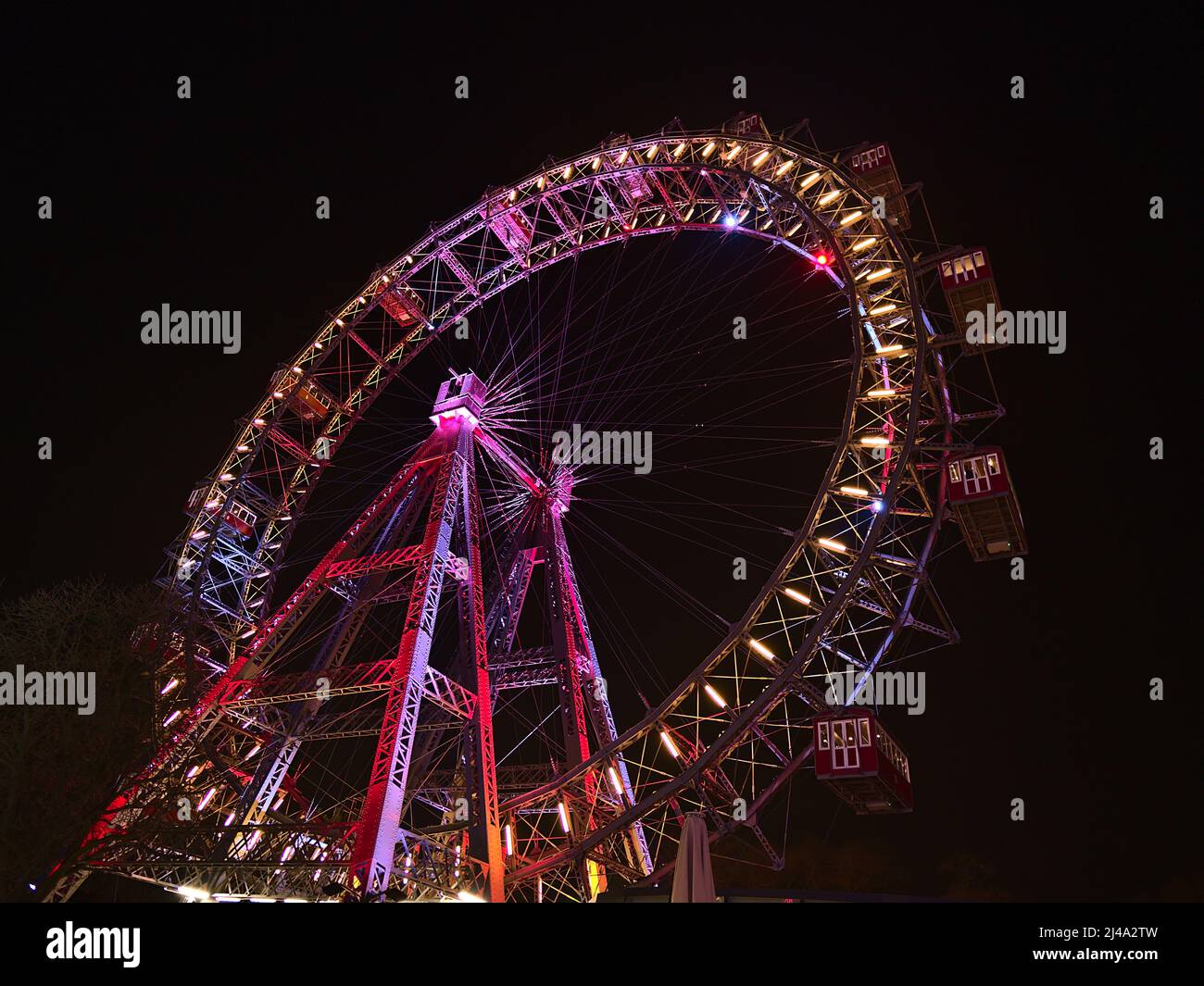 Splendida vista ad angolo basso della popolare ruota panoramica con bordo illuminato colorato di notte nel parco divertimenti Prater (Wurstelprater) a Vienna, Austria. Foto Stock