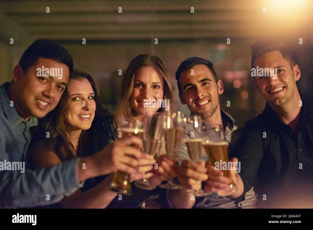 Heres a celebrare la vita. Ritratto di un gruppo di persone che tostano con le loro bevande in un nightclub. Foto Stock