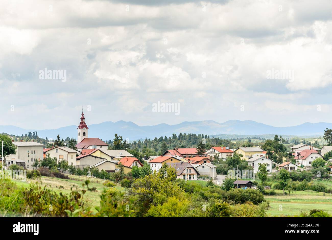 Bellissimo paesaggio nella campagna slovena. Villaggio pittoresco con cottage tradizionali e una Chiesa con Belfry in un ambiente naturale con tre Foto Stock