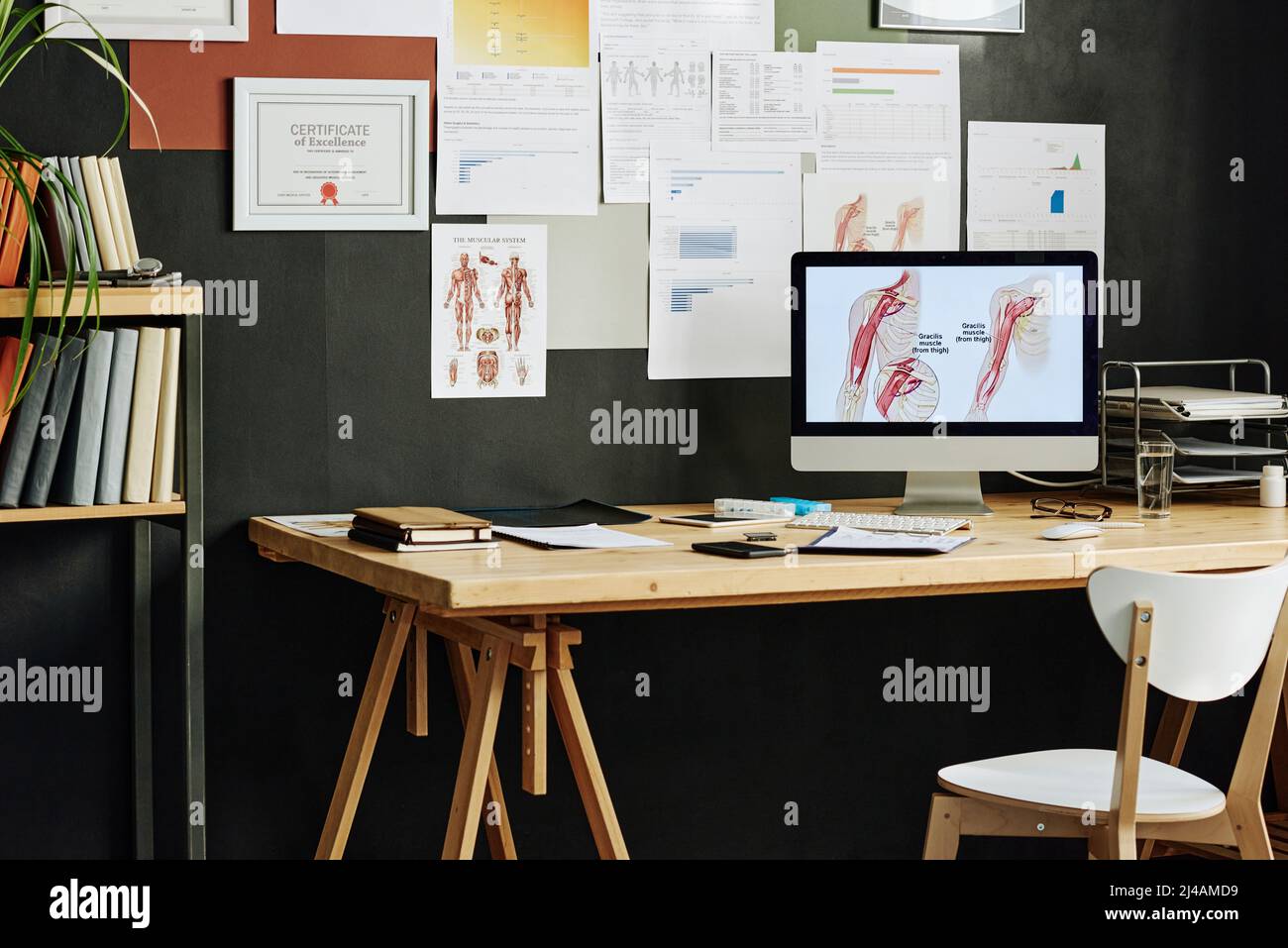 Spazio di lavoro vuoto con monitor per computer su di esso per la formazione online con poster della medicina a parete Foto Stock