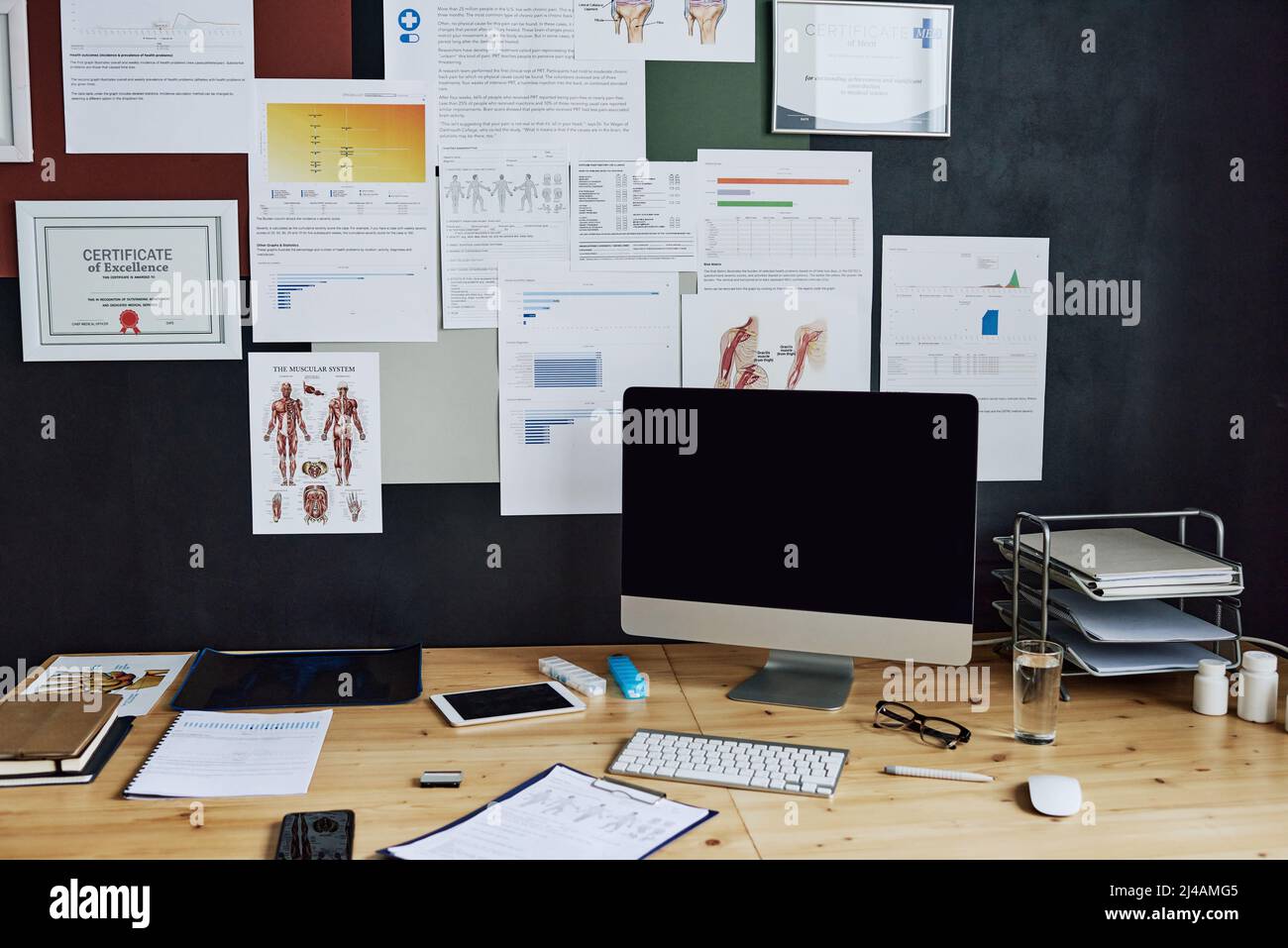 Ambiente di lavoro moderno in ufficio con monitor per computer e poster medici a parete per il medico Foto Stock