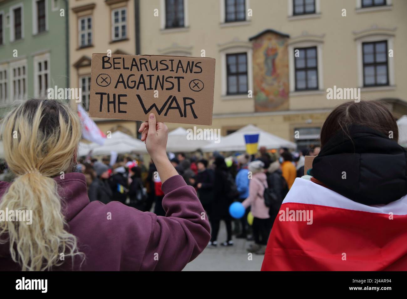 Protesta a Cracovia, Polonia, contro l'attacco russo all'Ucraina, due ragazze con bandiera usata dall'opposizione bielorussa e bandiera BIELORUSSA AGAINSTWAR Foto Stock