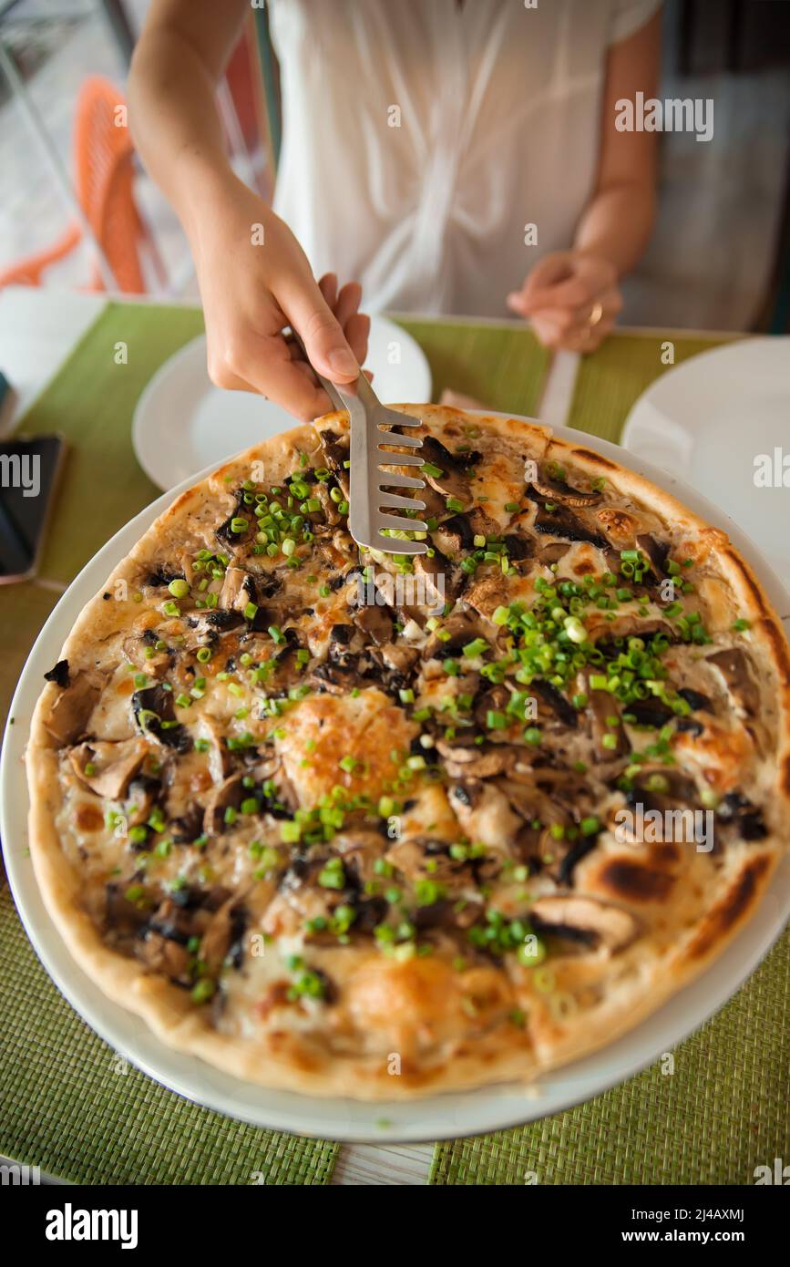 La gente prende le mani di fette di pizza. Tavolo con pizza in un ristorante. Pizza e mani si chiudono su sfondo verde. Foto Stock