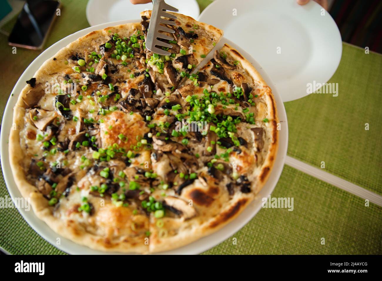 prendere fette di pizza. Tavolo con pizza in un ristorante. Pizza e mani si chiudono su sfondo verde. Foto Stock
