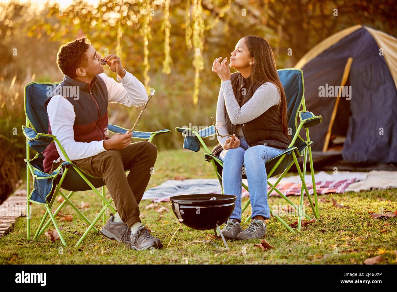 È tutto buono nei boschi. Shot di una giovane coppia torrefazione marshmallows durante il campeggio all'aperto. Foto Stock