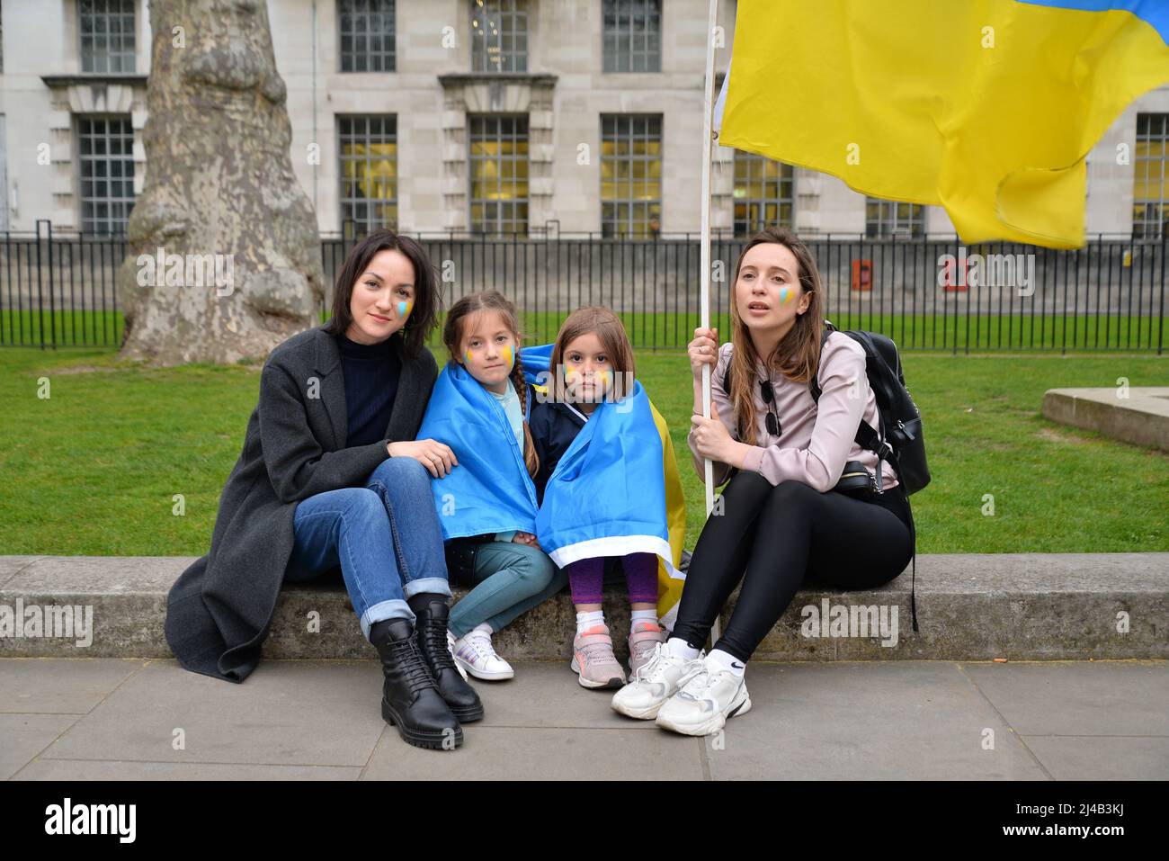 Londra, Regno Unito. 13th Apr 2022. A Whitehall di fronte a Downing Street, , cantando l'inno nazionale ucraino durante una protesta contro l'invasione russa dell'Ucraina - sulla sinistra, Natalia con sua figlia Elisabetta (6) si siede con i loro cugini - Olha e sua figlia Mira (6) che sono arrivati nel Regno Unito come rifugiati da Kiev 2 giorni fa. Credit: Mark York/Alamy Live News Foto Stock