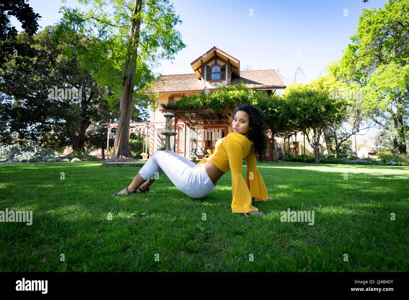 Ritratto di una giovane donna nera vibrante di fronte a una vecchia casa vittoriana Foto Stock