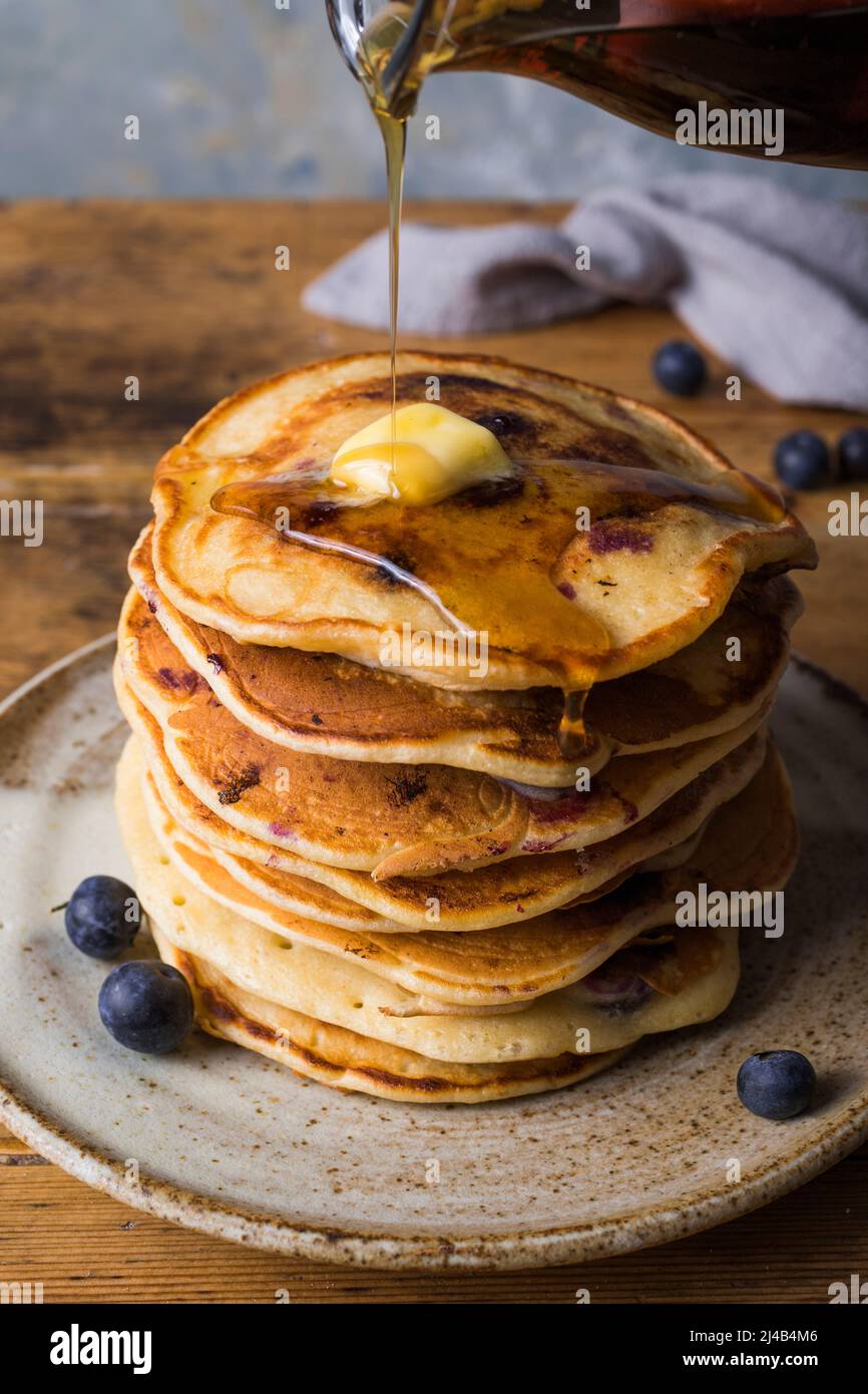 Pila di pancake al mirtillo che vengono gocciolati con sciroppo Foto Stock