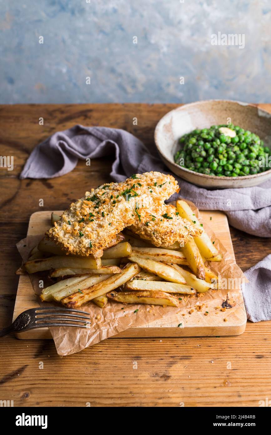 Pesce e patatine fatti in casa su un asse di legno Foto Stock