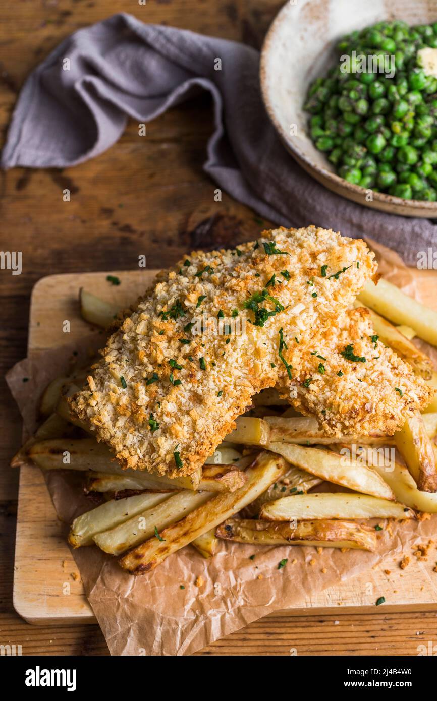Pesce e patatine fatti in casa su un asse di legno Foto Stock
