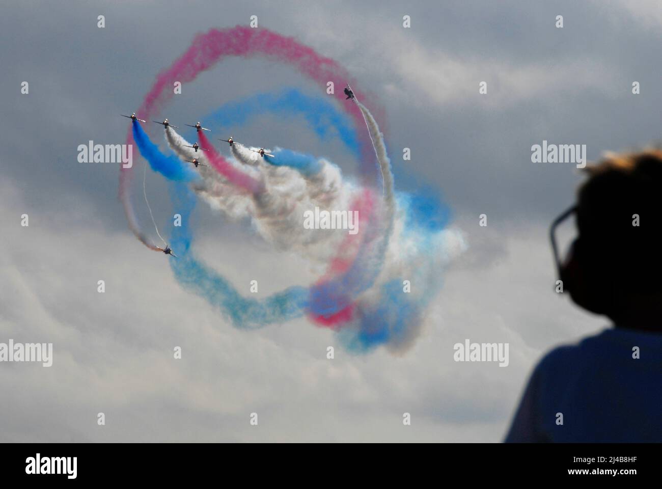 La squadra aerobatica RAF Red Arrows che offre un display con due aerei che eseguono un giro intorno ai restanti sette, tutti fumanti di colore trainato Foto Stock