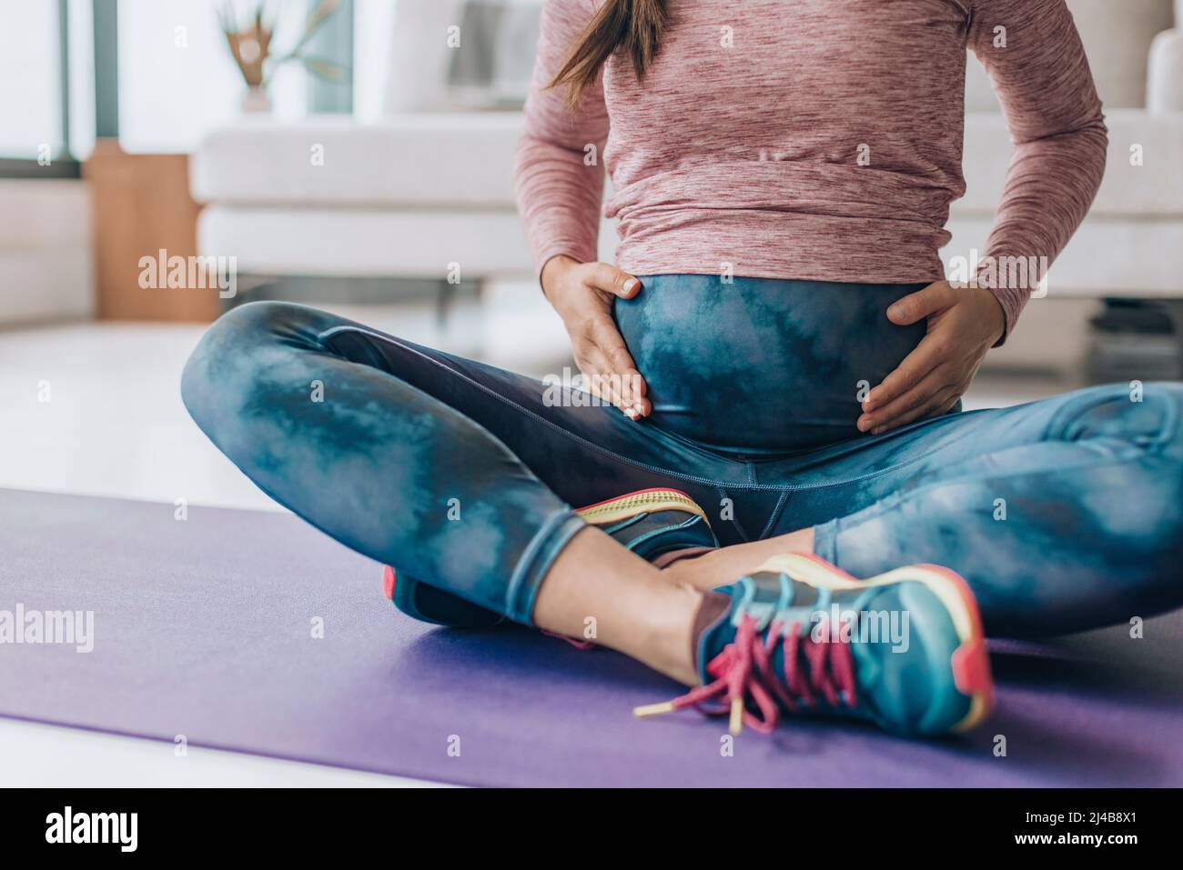 Abbigliamento sportivo per la gravidanza. Maternità abbigliamento donna indossando pieno pannello yoga leggings per il peso corporeo di allenamento a casa sul tappetino Foto Stock
