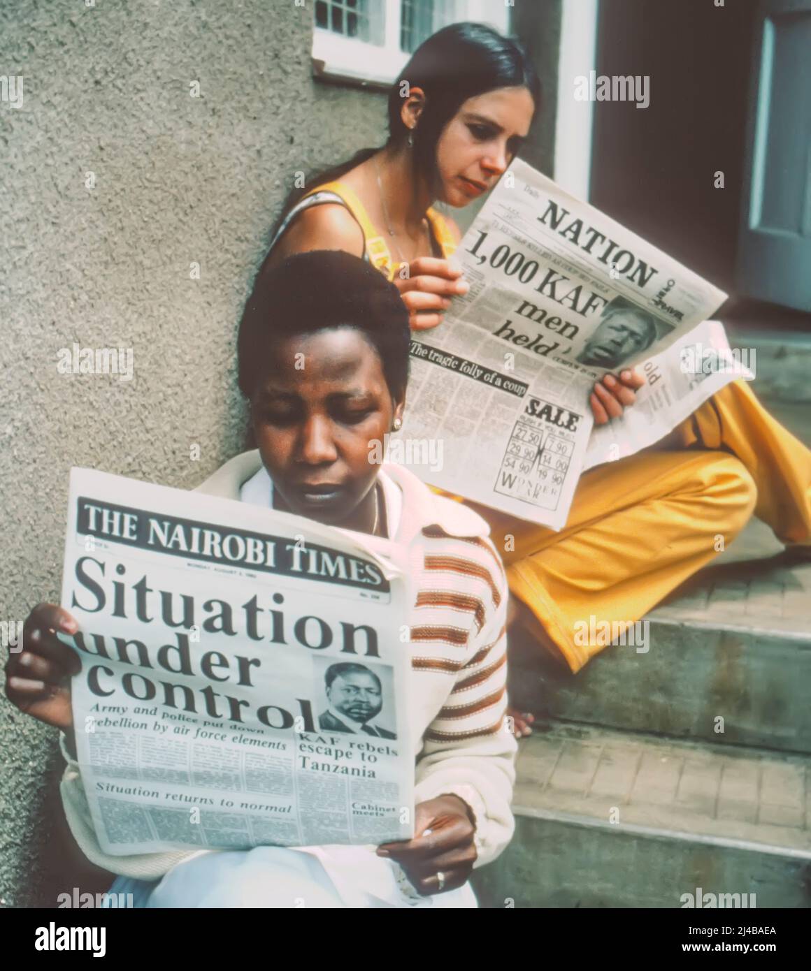 Due donne leggono notizie del tentativo di colpo di stato militare in Kenya 1982 Foto Stock