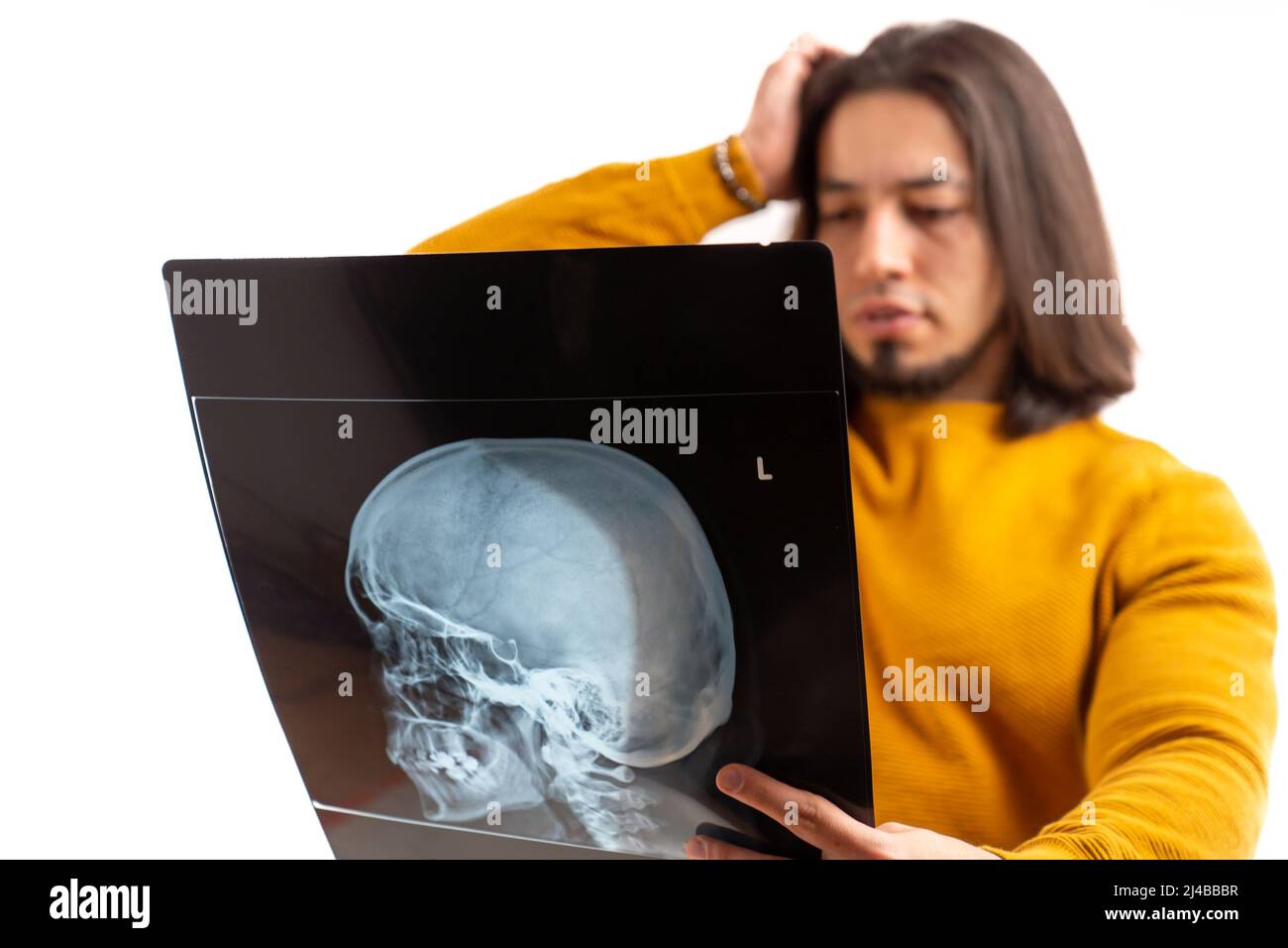 Paziente europeo che guarda da vicino la testa radiografica, tocca la testa con la sua mano, isolato studio shot . Foto di alta qualità Foto Stock