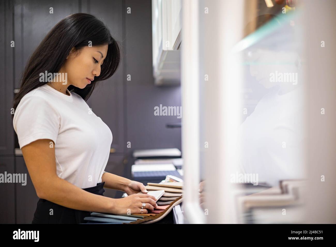 Asian donna interior designer sceglie il colore di pietra countertop per la cucina o facciate Foto Stock