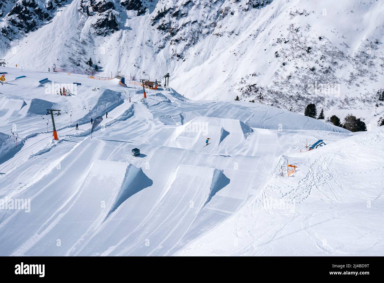 Vista ad alto angolo della pista di risalita sul paesaggio innevato delle alpi in giornata di sole Foto Stock