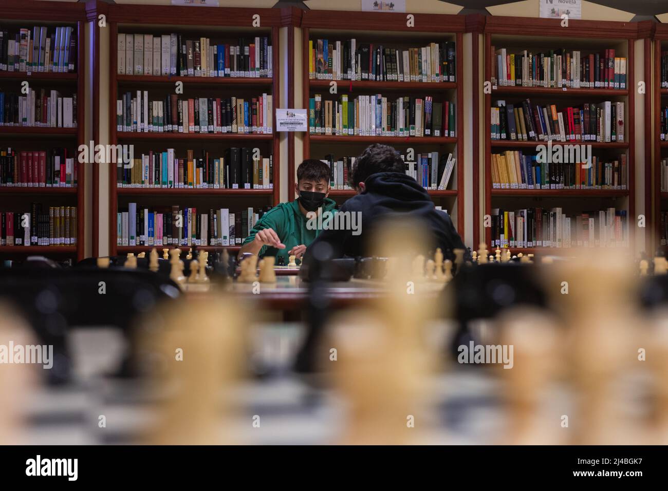Concorso di scacchi su una biblioteca, due studenti che giocano una partita Foto Stock