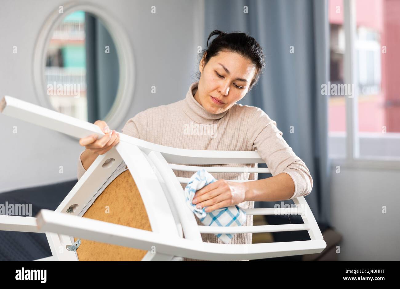 Donna asiatica asciuga una sedia con un panno umido Foto Stock