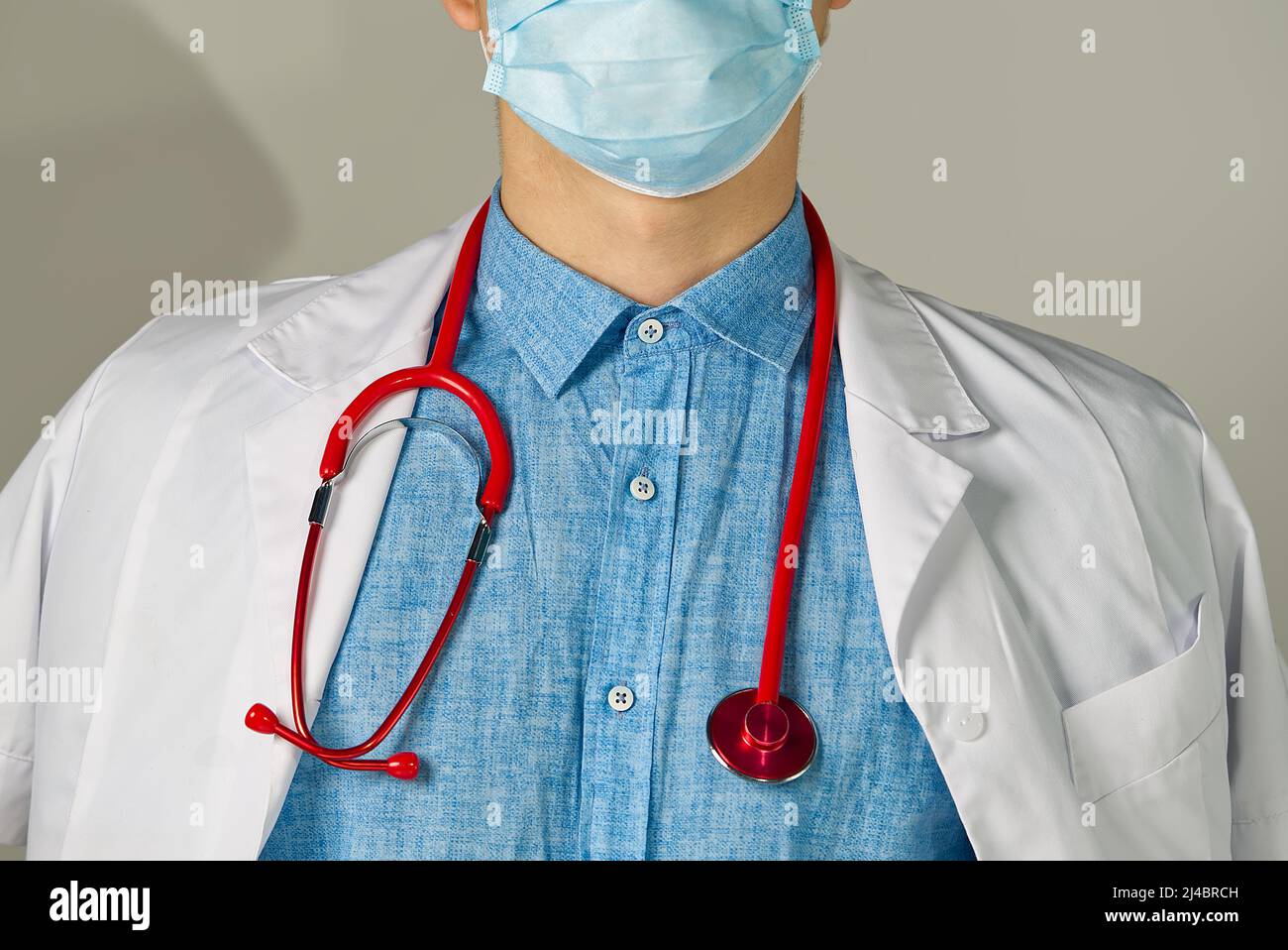 medico giovane irriconoscibile in piedi su sfondo chiaro Foto Stock