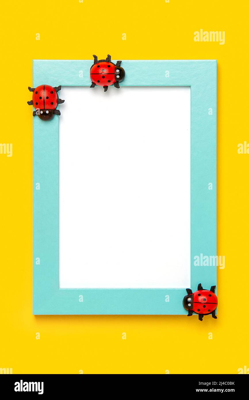 Cornice blu con cartoncino bianco e ladybugs su sfondo giallo. Mockup, Vista dall'alto, disposizione piatta. Layout, modello per il progetto. Foto Stock