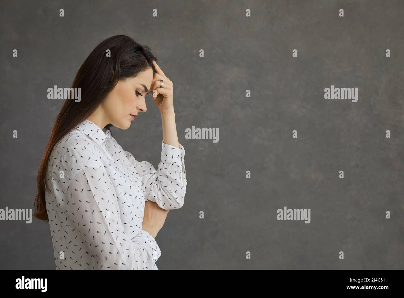 Vista del profilo di una donna pensiva triste che tocca la testa pensando ai suoi problemi. Foto Stock