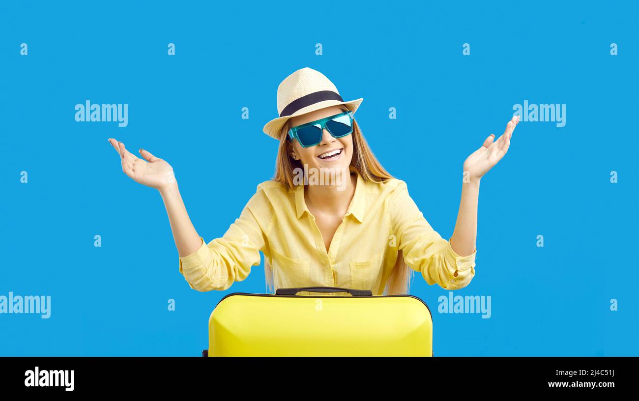 Bella ragazza turistica giovane felice in cappello e occhiali da sole in vacanza con la sua valigia Foto Stock