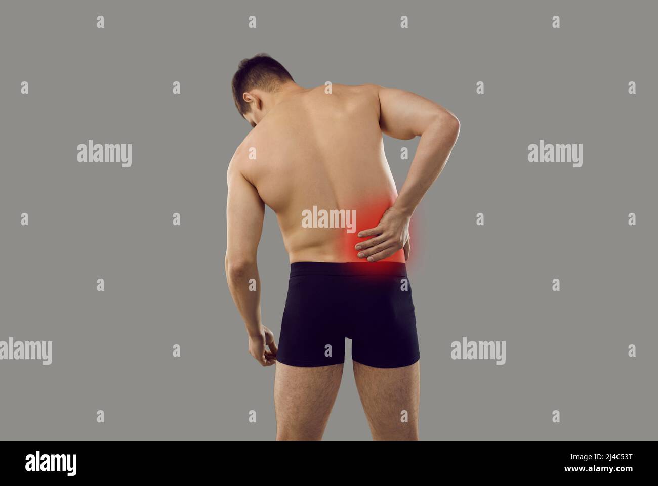 Vista posteriore dell'uomo che soffre di dolore nel suo lato destro isolato su sfondo grigio Foto Stock