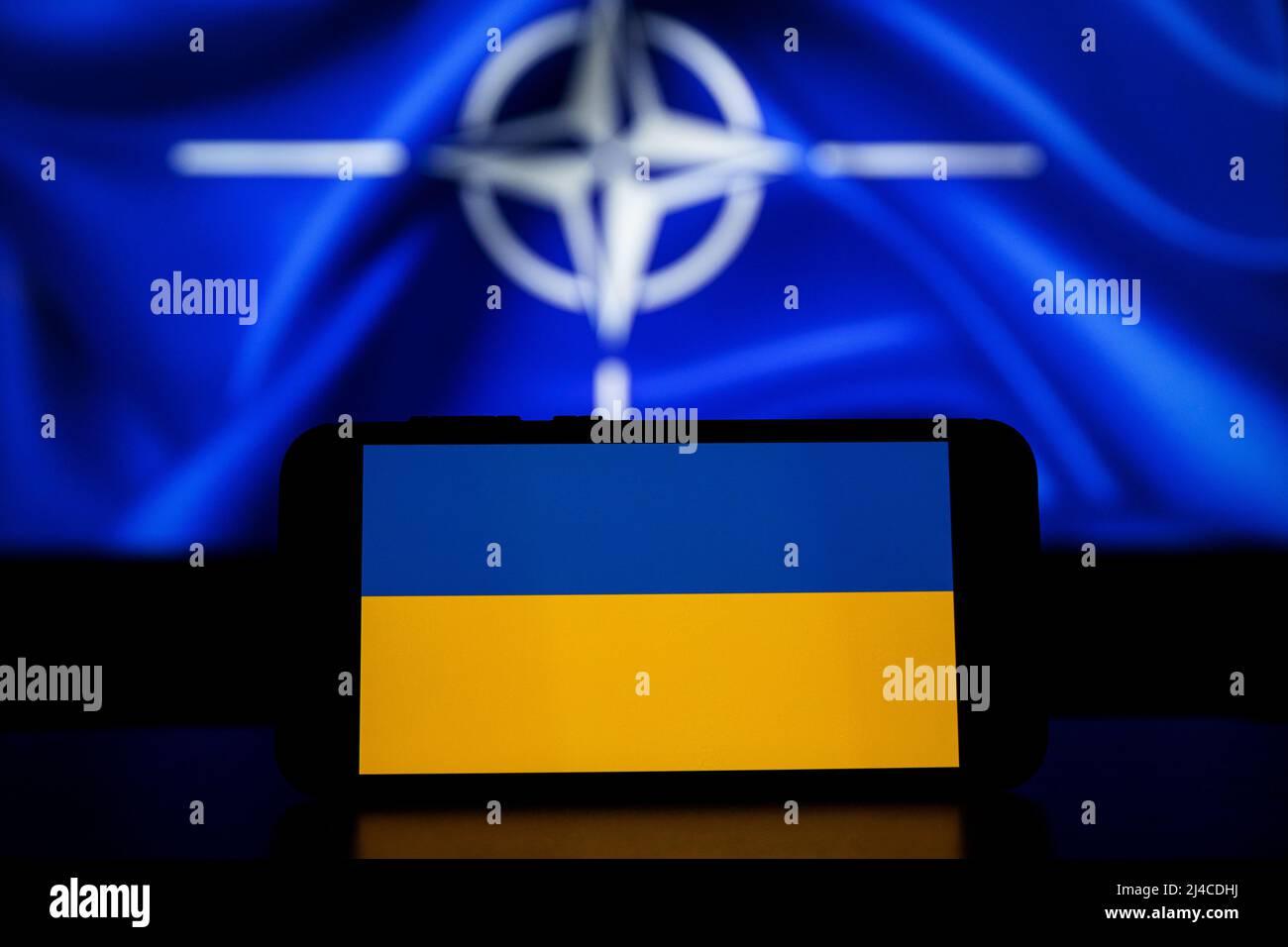 L'Organizzazione del Trattato del Nord Atlantico sugli schermi. Bandiera Ucraina sullo schermo e bandiera NATO sullo sfondo Foto Stock