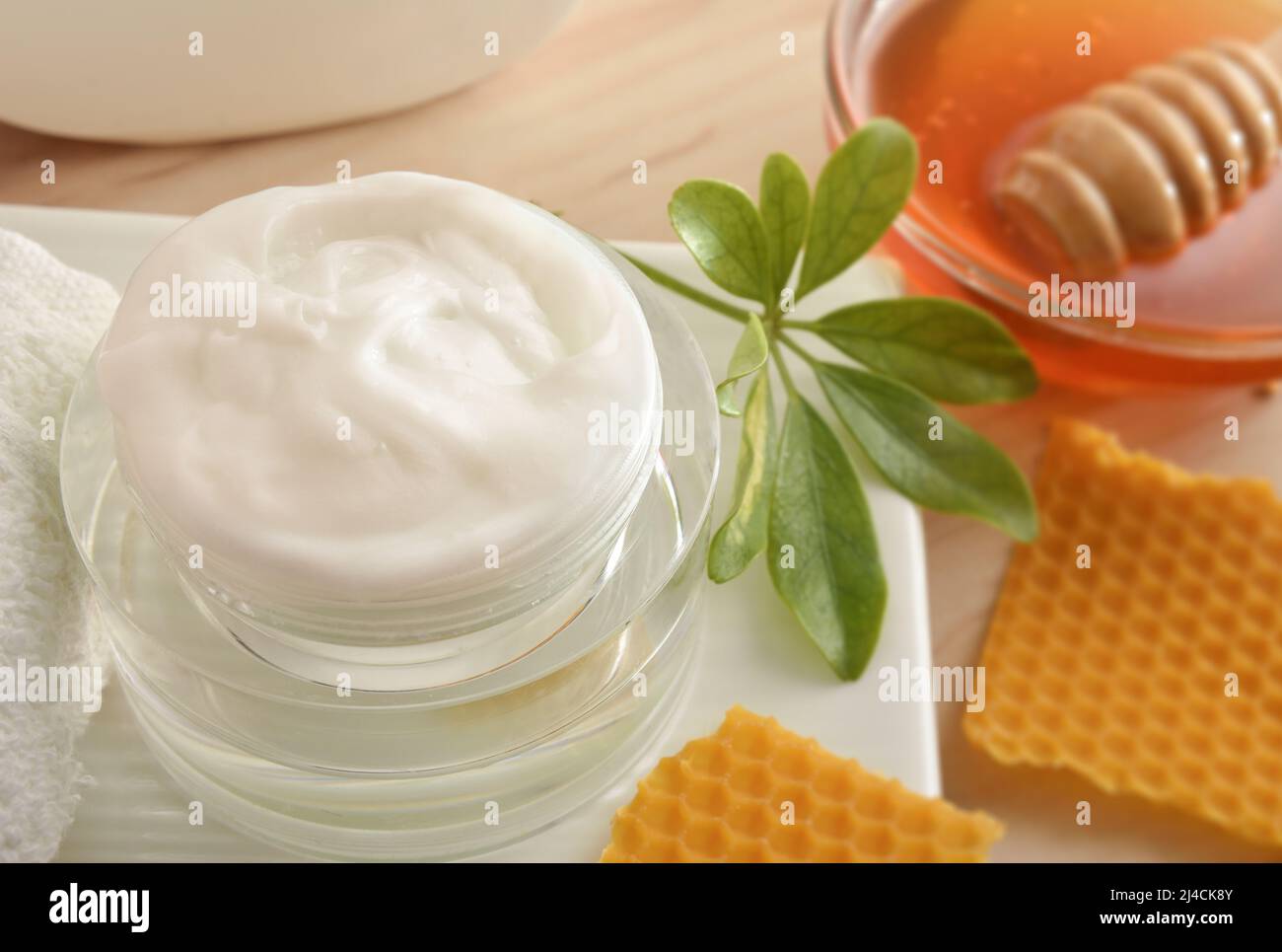 Crema con estratti di miele e contenitore con miele su tavola di legno. Composizione orizzontale. Vista rialzata. Foto Stock