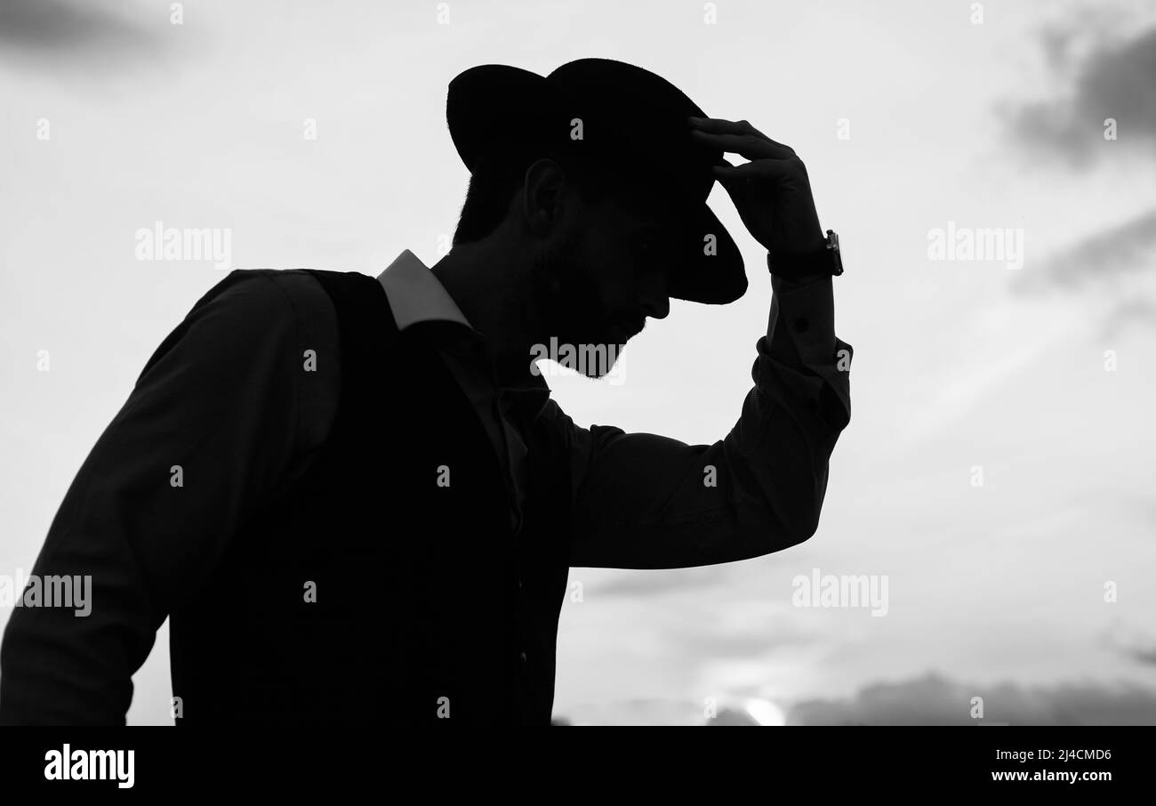 silhouette ballerina uomo posa con cappello contro il cielo del tramonto, silhouette Foto Stock