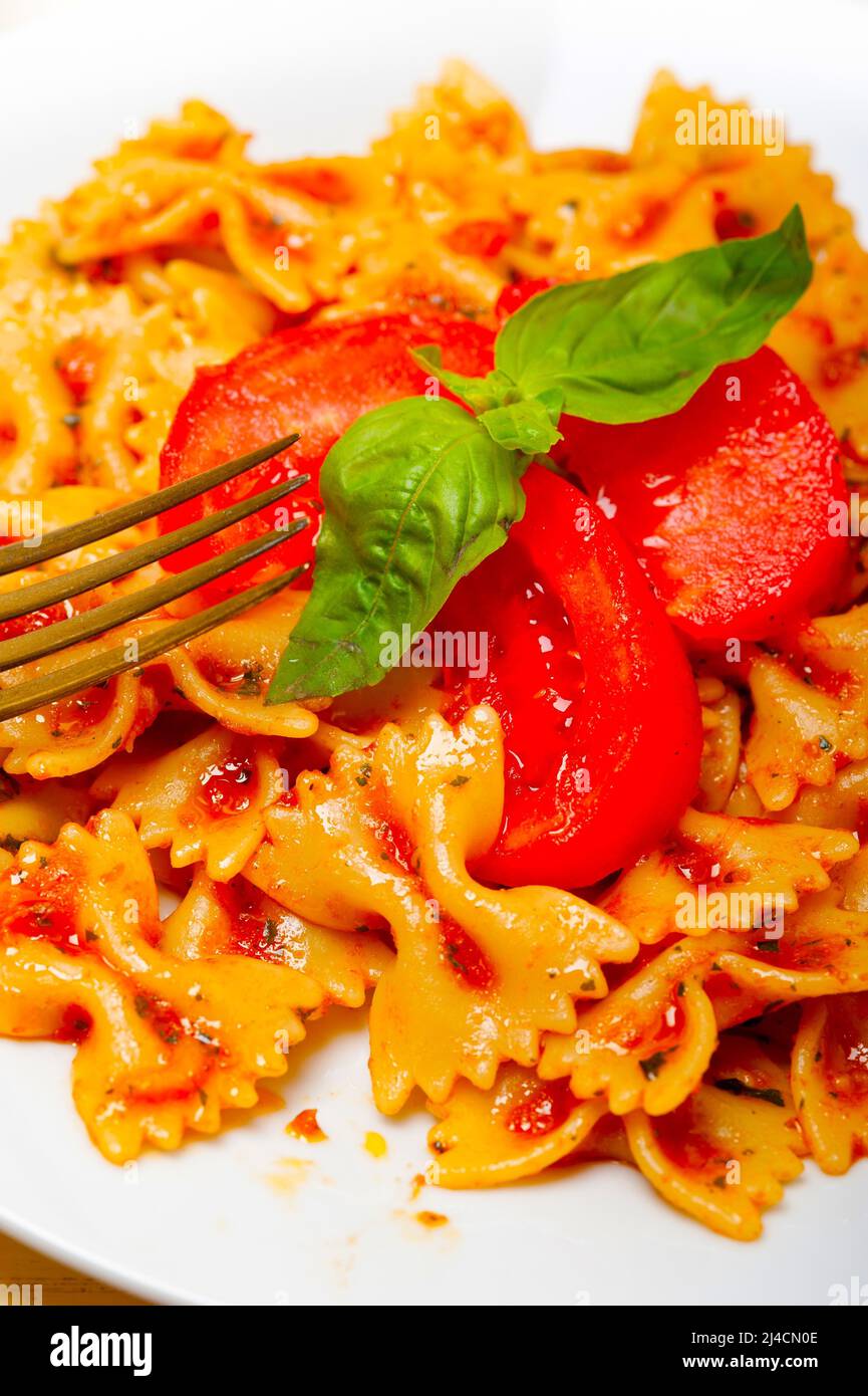 La pasta italiana Le farfalle butterfly bow tie-in pomodoro con salsa al basilico bianco su tavola in legno rustico Foto Stock
