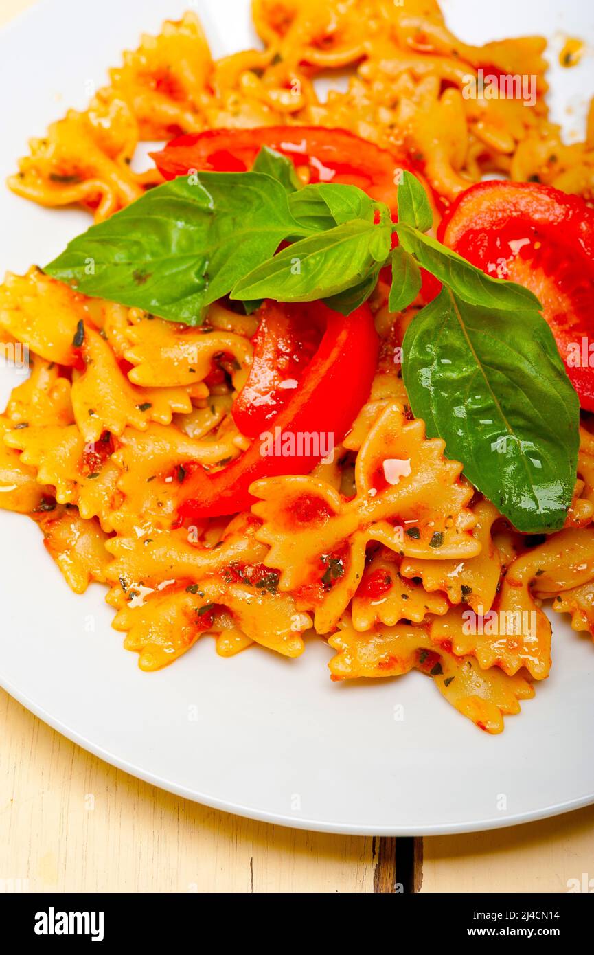 La pasta italiana Le farfalle butterfly bow tie-in pomodoro con salsa al basilico bianco su tavola in legno rustico Foto Stock