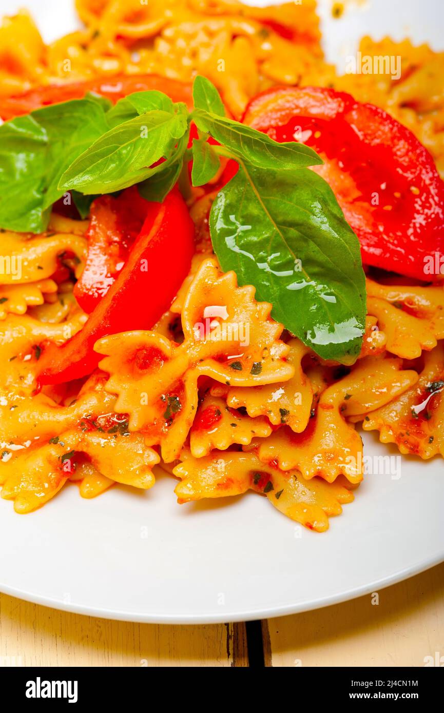 La pasta italiana Le farfalle butterfly bow tie-in pomodoro con salsa al basilico bianco su tavola in legno rustico Foto Stock