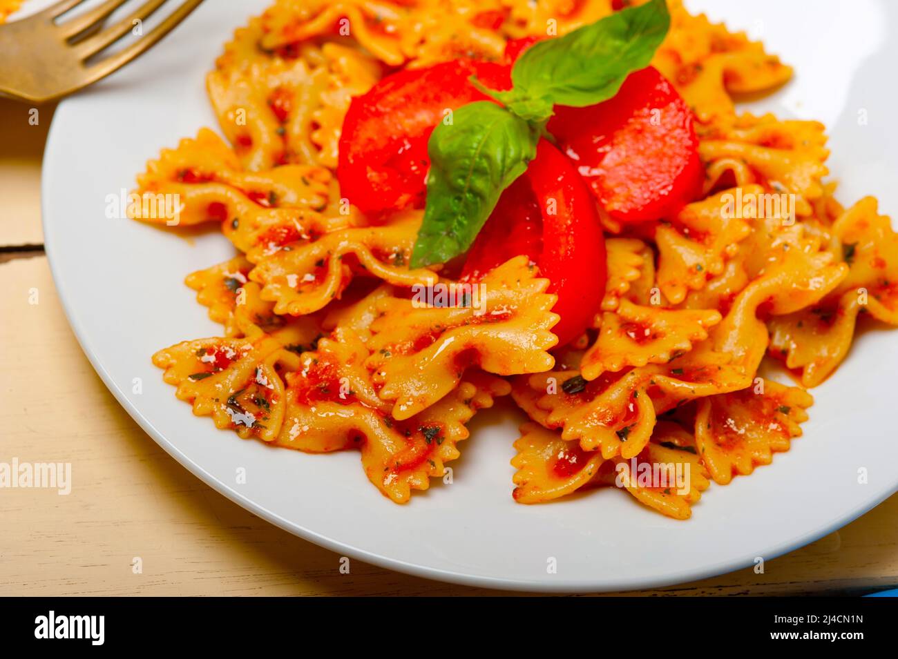 La pasta italiana Le farfalle butterfly bow tie-in pomodoro con salsa al basilico bianco su tavola in legno rustico Foto Stock