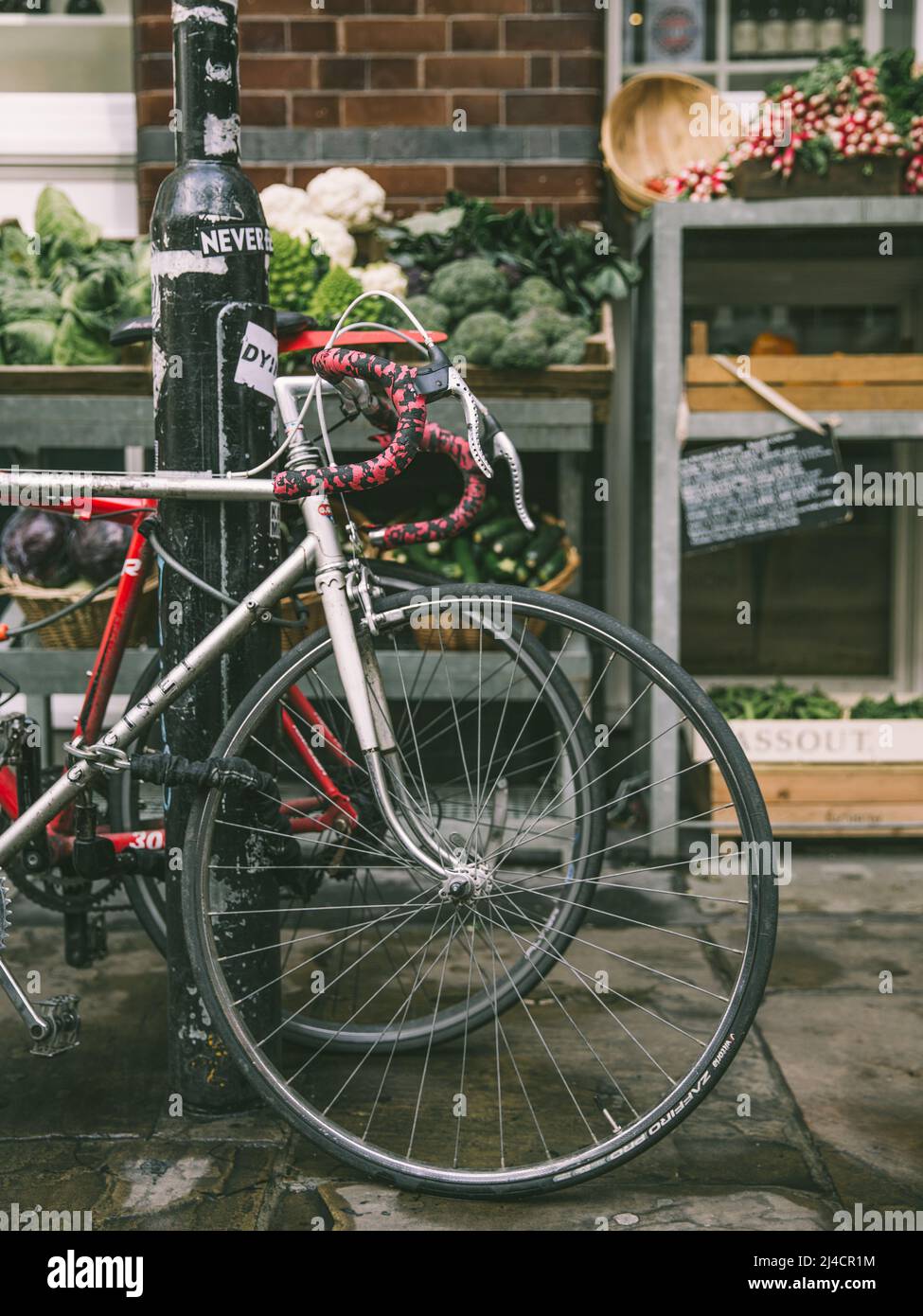 Greater London, London, UK - 14 aprile 2016: Una bicicletta da strada stazionaria è visto in primo piano di questa scena stradale di East London, con un frutto e. Foto Stock