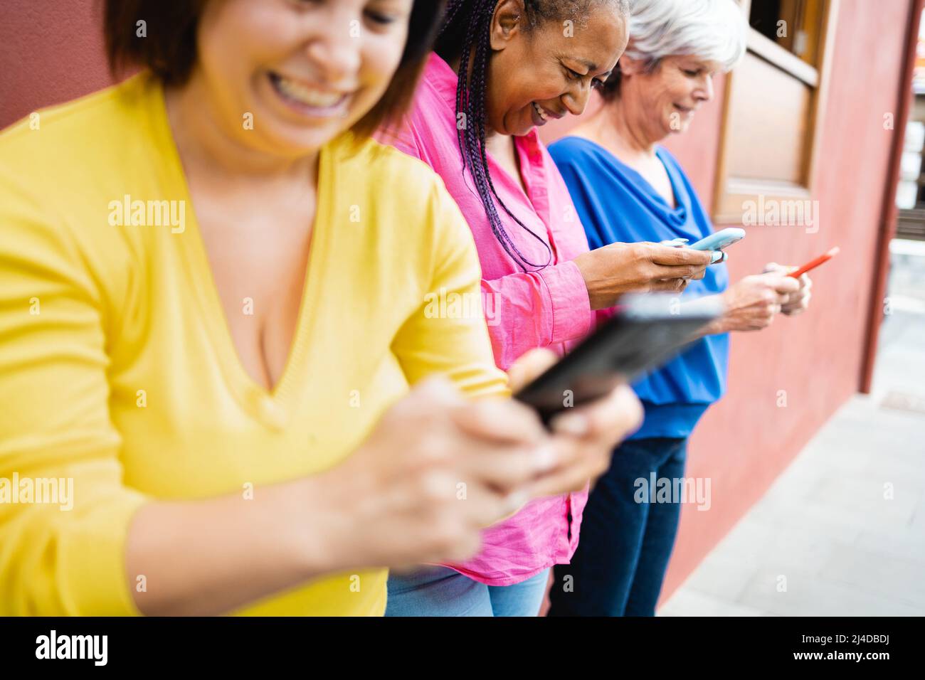Buone donne multirazziali anziane che usano i telefoni cellulari all'aperto - Focus on African female face Foto Stock