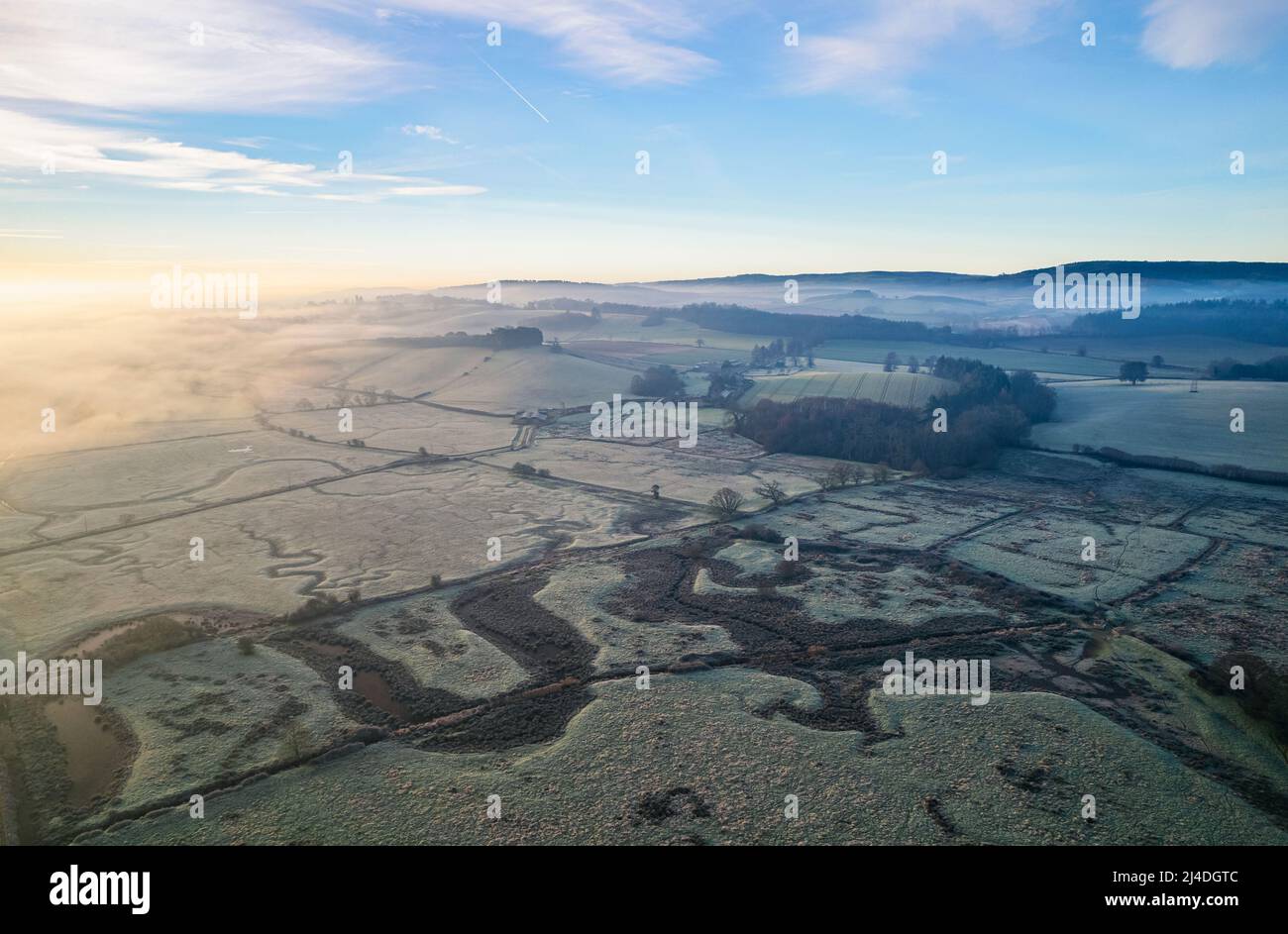 Misty Sunrise sopra le paludi e i prati ghiacciati, RSPB Exminster e Powderham Marshe da un drone, Exeter, Devon, Inghilterra Foto Stock