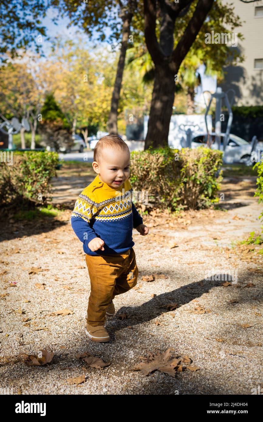 Divertente bambino che gioca al parco giochi all'aperto. Bambino che cammina. Giorno di sole Foto Stock